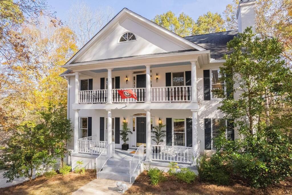 een wit huis met een veranda en een balkon bij Large Luxury House, 4 King Beds & 21 Total, Hot Tub, Theater, Fireplace, Game Room, Ping-pong, Pool Table, Air Hockey, Arcade, River, Big Kitchen, Nice Porch, Quiet, Good for Families and Large Groups, Near UGA Golf Course, Close to UGA & Stanford Stadium in Athens