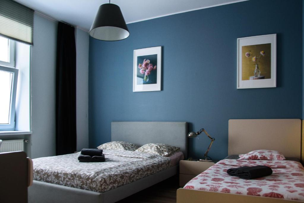 two beds in a room with blue walls at Milo Mi - 2 Bedroom Apartment in the Old Town in Poznań