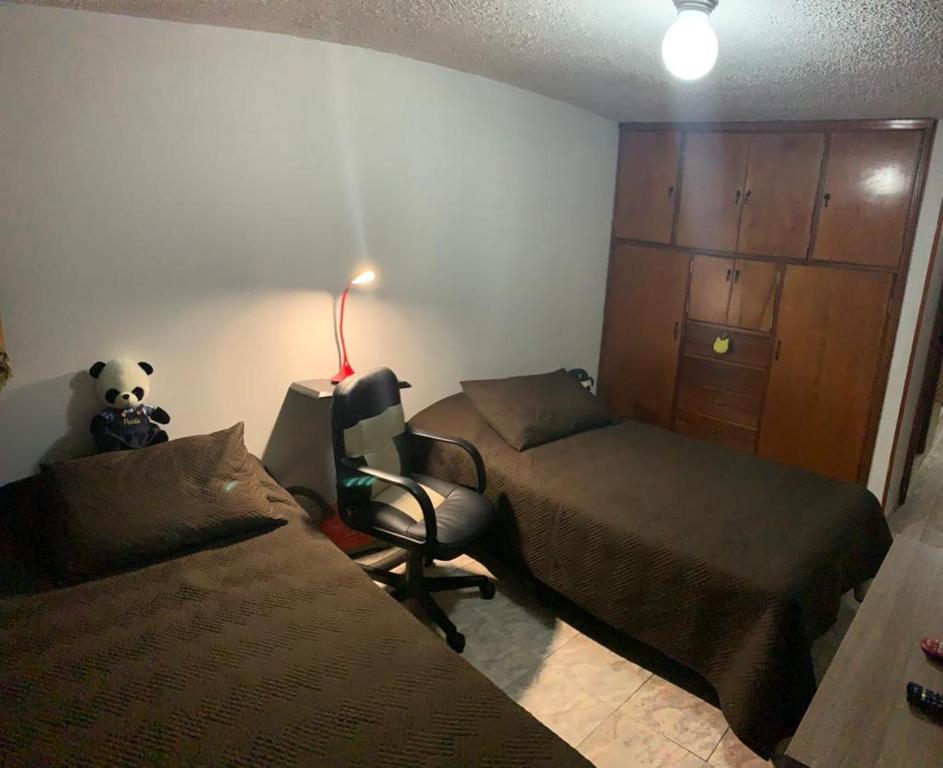 1 dormitorio con 2 camas, silla y lámpara en cómoda habitación cerca al aeropuerto, en Bogotá