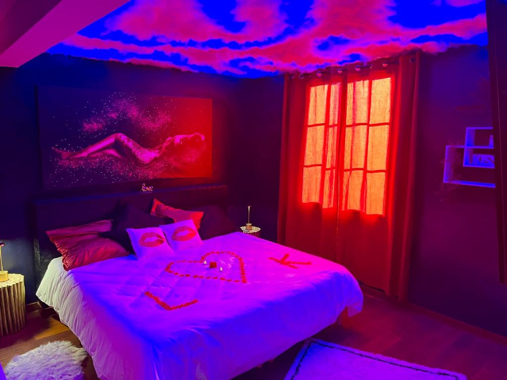 a bedroom with a bed with pink lights on it at Escapade jacuzzi in Caen
