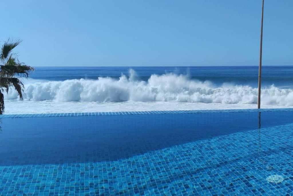 a swimming pool next to the ocean with waves at Villa Sunset Avenue in Paul do Mar