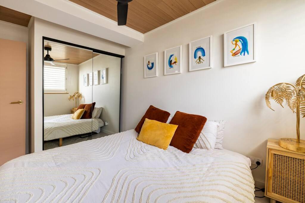 um quarto com uma cama branca e um espelho em Chic beachside getaway 2BR 2Bath Fully Equipped em Gold Coast