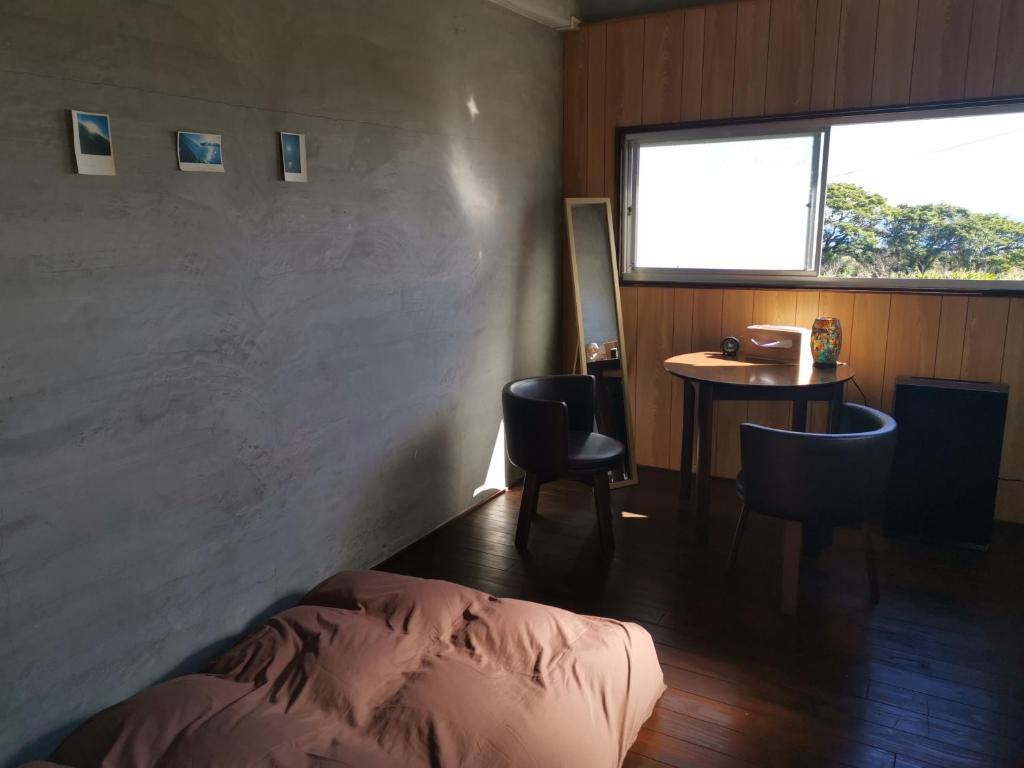 Schlafzimmer mit einem Bett, einem Tisch und einem Fenster in der Unterkunft Umi no Mieru Ie Ocean View in Nishinoomote