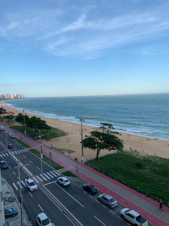 a road with cars parked next to a beach at A dois passos do mar… in Vila Velha