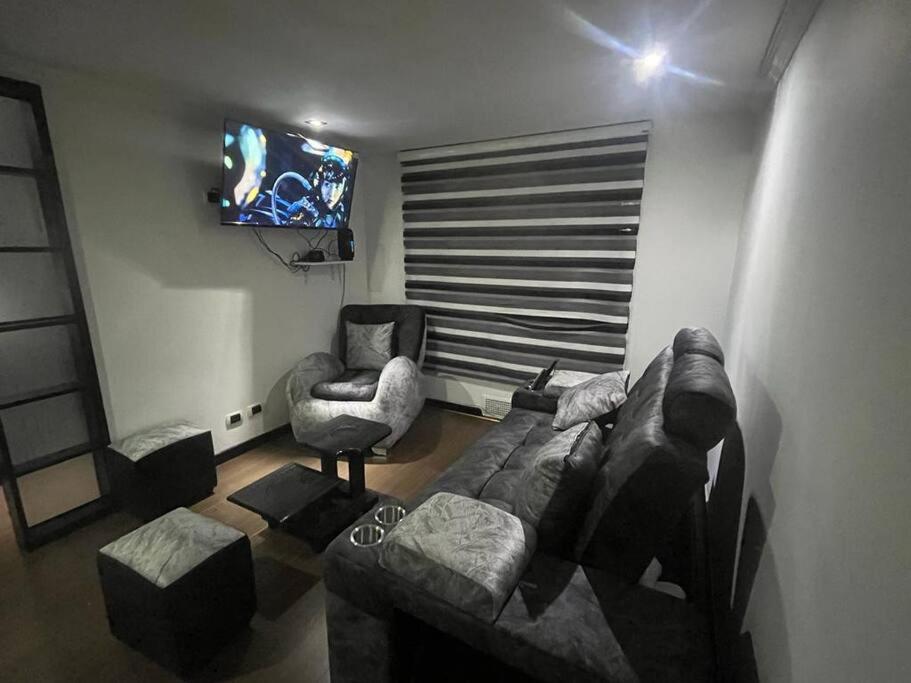 a living room with a couch and a chair and a television at Acogedor Apto Sector Tintal in Bogotá