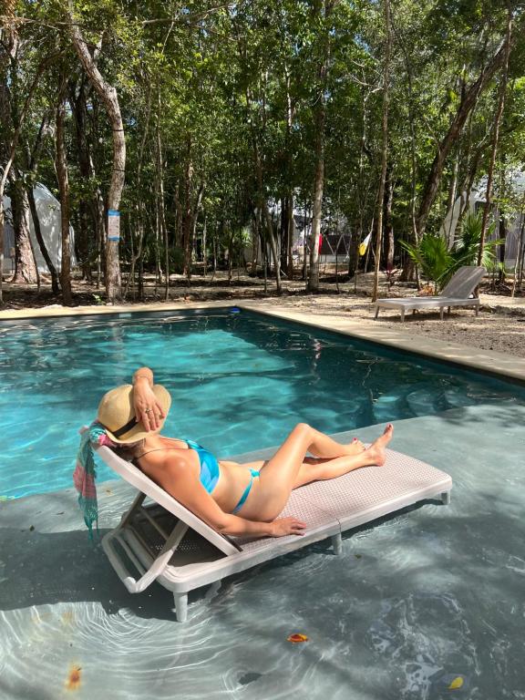 a woman laying on a raft in a swimming pool at Glamping Mayan Glam in Tulum
