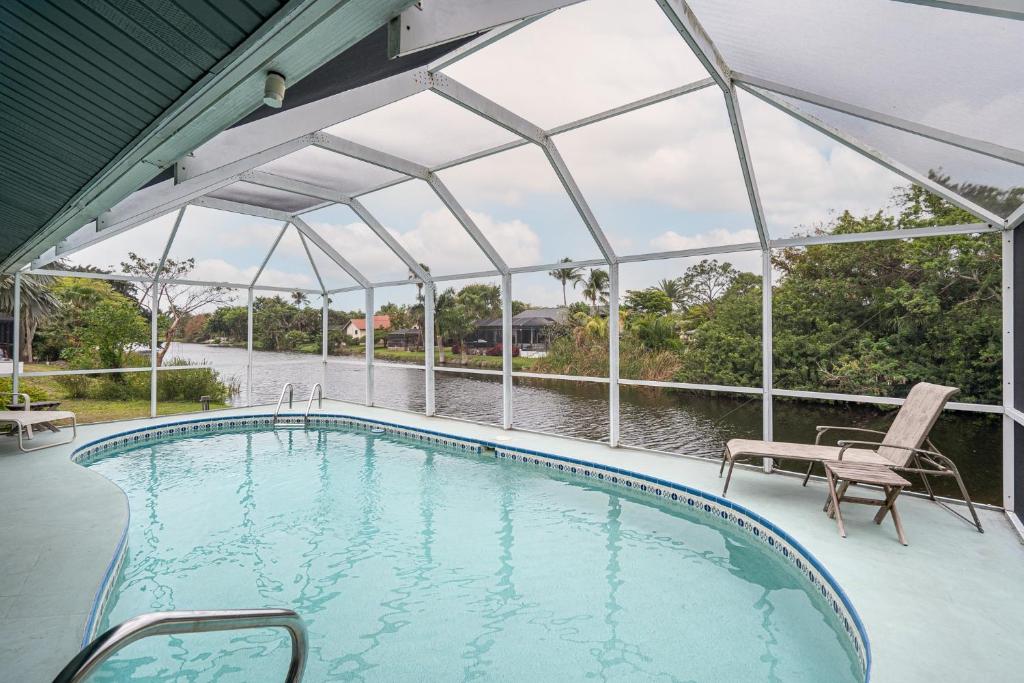 a swimming pool with a pergola next to a body of water at Private Pool Home - Just Miles from Sanibel and Fort Myers Beach - home in Fort Myers