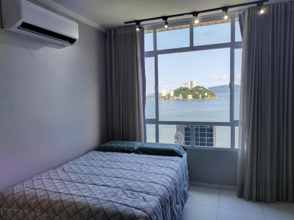 a bedroom with a bed and a large window at Mirante de São Vicente in São Vicente