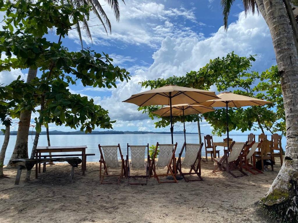 a beach with chairs and tables and umbrellas at Family Cabana at Amihan Surf Cabanas in General Luna