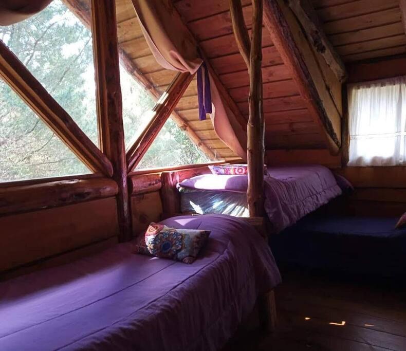 a bedroom with two beds in a wooden cabin at Cabaña Mirador del Valle in Lago Puelo