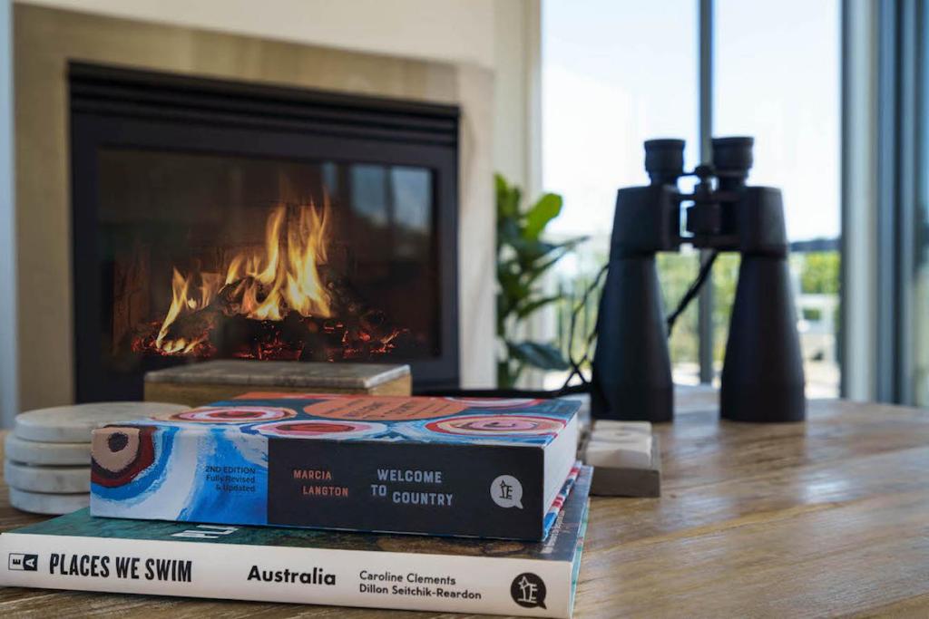 a table with two books and a camera and a fireplace at Bass Vista in Cape Schanck