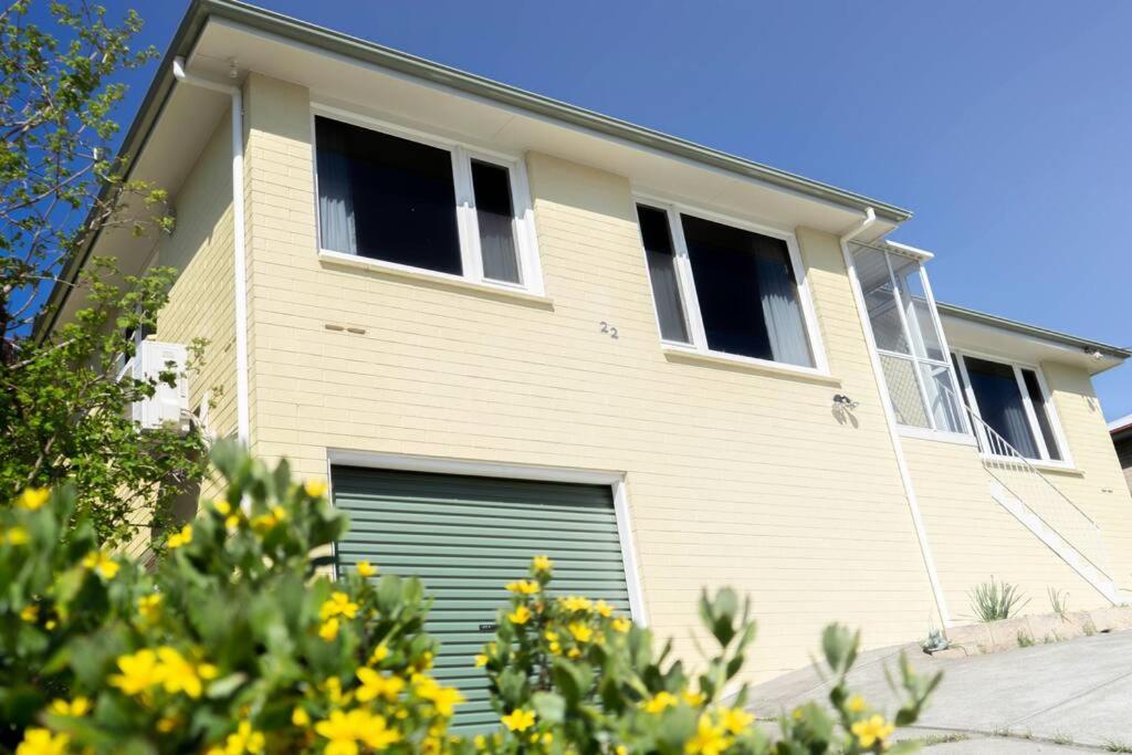 une maison jaune avec une porte de garage verte dans l'établissement Sunny, Spacious mountain views, Holiday home, à Lenah Valley