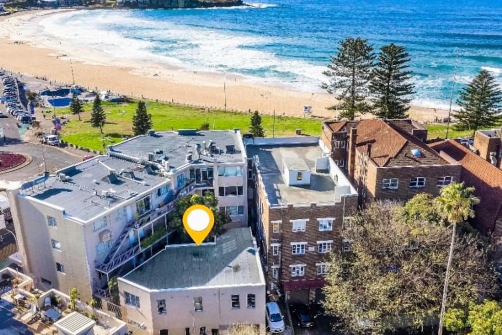 a building with a yellow sign on it next to a beach at Large 4 Bed Beachside Haven 50m to Bondi Beach in Sydney