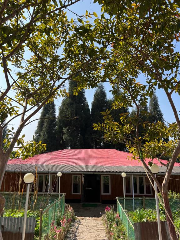 a house with a red roof with trees in the background at Dilpali Home Cum Farm stay in Sukhia Pokhari