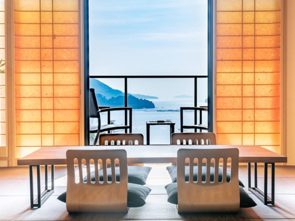 a table and chairs in a room with a large window at LiVEMAX RESORT Miyahama Ocean View in Hatsukaichi