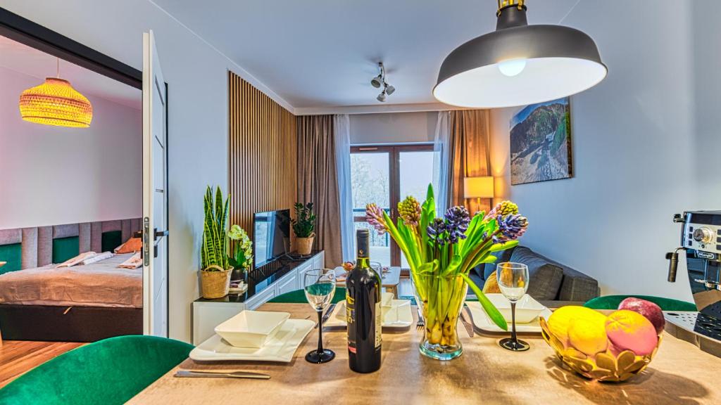 a dining room with a table with flowers and wine glasses at Apartament D19 z Basenem, Sauną, Jacuzzi Green Park Resort - 5D Apartments in Szklarska Poręba