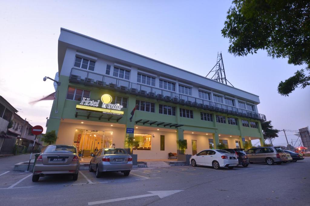 ein großes Gebäude mit Autos auf einem Parkplatz in der Unterkunft Hotel Pintar in Parit Raja