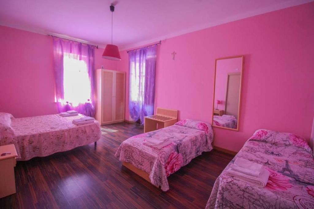 um quarto rosa com 2 camas e um espelho em Casa Margherita em Sellia Marina