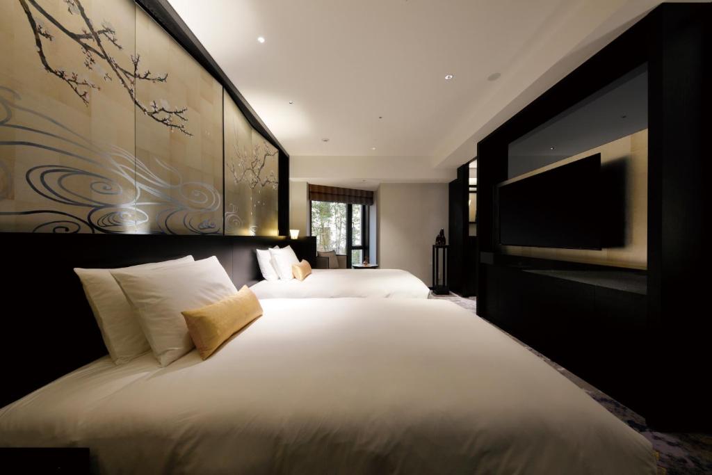 a bedroom with two beds and a flat screen tv at THE HOTEL SANRAKU KANAZAWA 21th December 2022 OPEN in Kanazawa