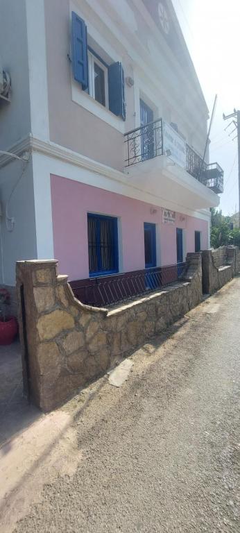a white building with blue windows and a stone wall at "STELIOS & GALINI" in Symi
