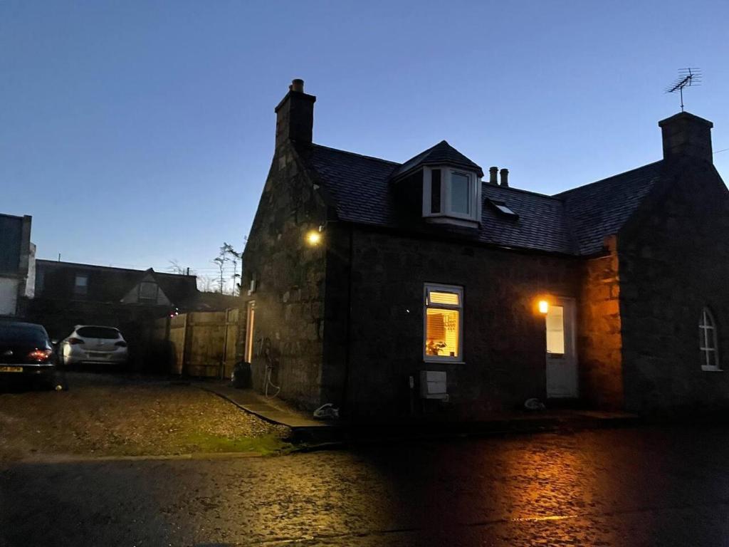 una casa con un coche aparcado delante de ella en Rural Chapel Cottage near airport bar & hot tub en Aberdeen