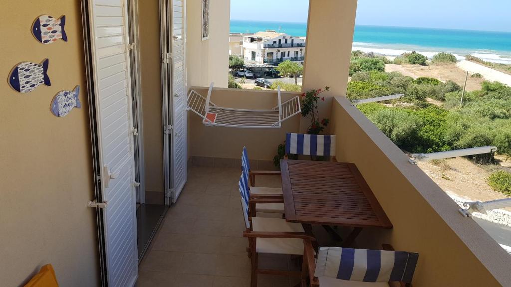 einen Balkon mit Tisch und Stühlen sowie Strand in der Unterkunft Casa CostaSud in Marina di Ragusa