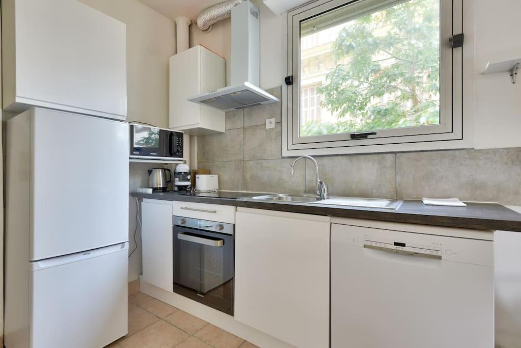 a white kitchen with a sink and a window at Superbe studio Vieux Nice 1 min à pied de la plage in Nice