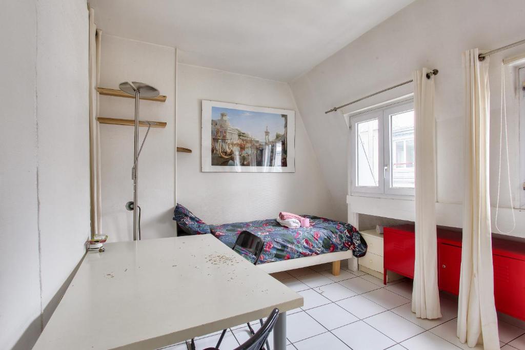 ein kleines Zimmer mit einem Tisch und einem Bett in der Unterkunft Cosy studio in the 8th arr 4 min from Rome metro in Paris