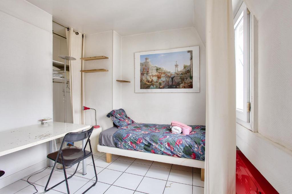ein kleines Schlafzimmer mit einem Bett und einem Schreibtisch in der Unterkunft Cosy studio in the 8th arr 4 min from Rome metro in Paris