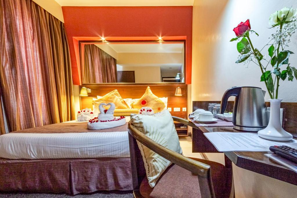 a hotel room with a bed with a desk and a mirror at Hotel Rio in Nairobi