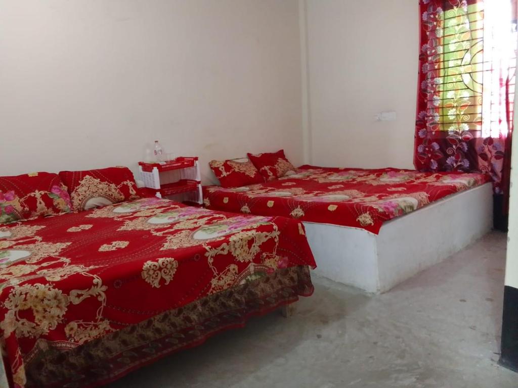 duas camas num quarto com cobertores vermelhos e janelas em Kuakata Hotel & Resort em Kuakata