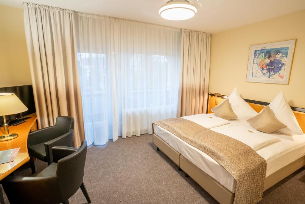 a hotel room with a bed and a desk and a window at Hotel am Stadtgarten in Radolfzell am Bodensee