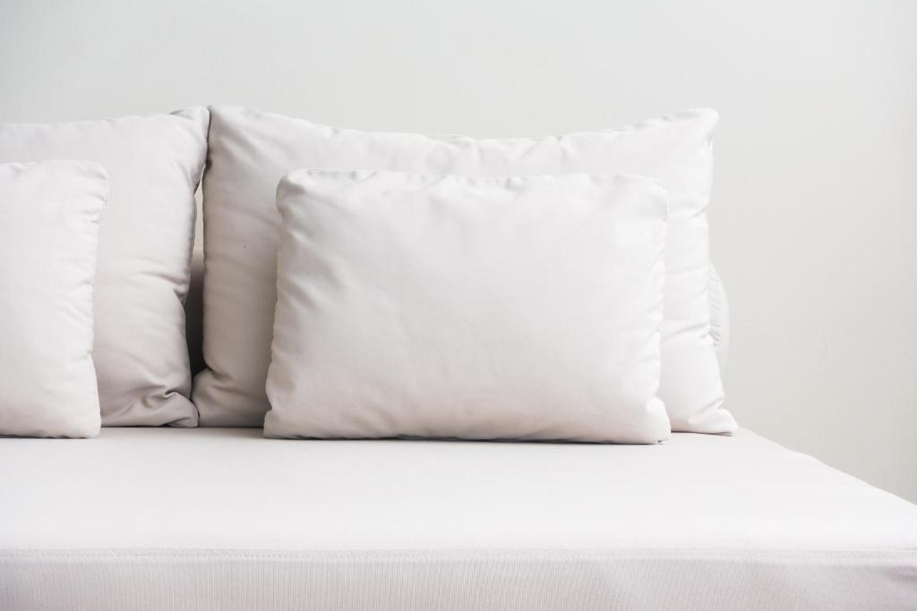 una pila de almohadas blancas en una cama en Core Luxembourg City, en Luxemburgo