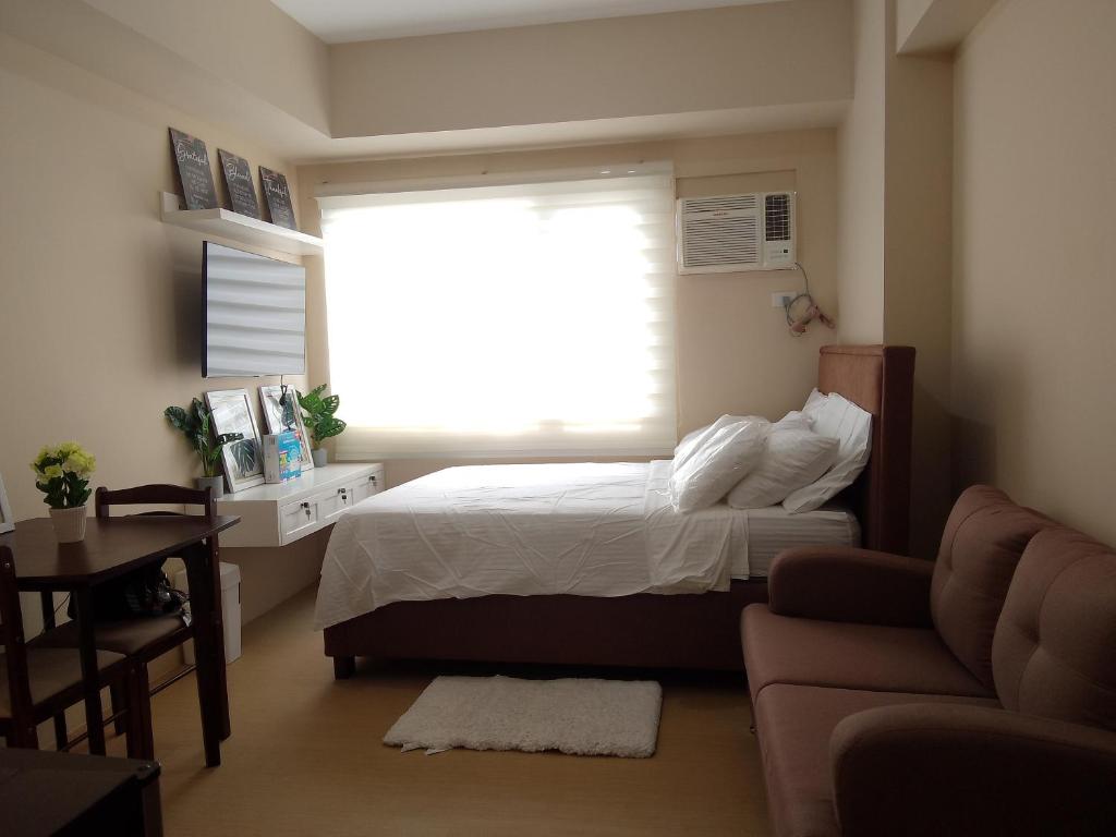 1 dormitorio con cama y ventana grande en LPP CONDO UNIT AT AVIDA ASPIRA CONDOMINIUM, en Cagayan de Oro