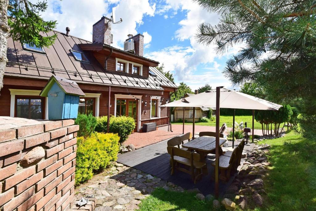 un patio con una mesa y una sombrilla frente a una casa en Spa Villa Trakai en Trakai