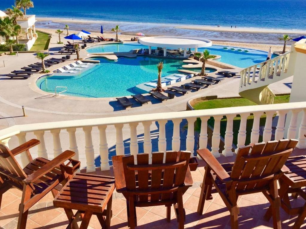 un balcon avec des chaises, une piscine et la plage dans l'établissement Stunning 4 Bedroom Beach Villa on Sandy Beach at Las Palmas Beach Resort V14 villa, à Puerto Peñasco