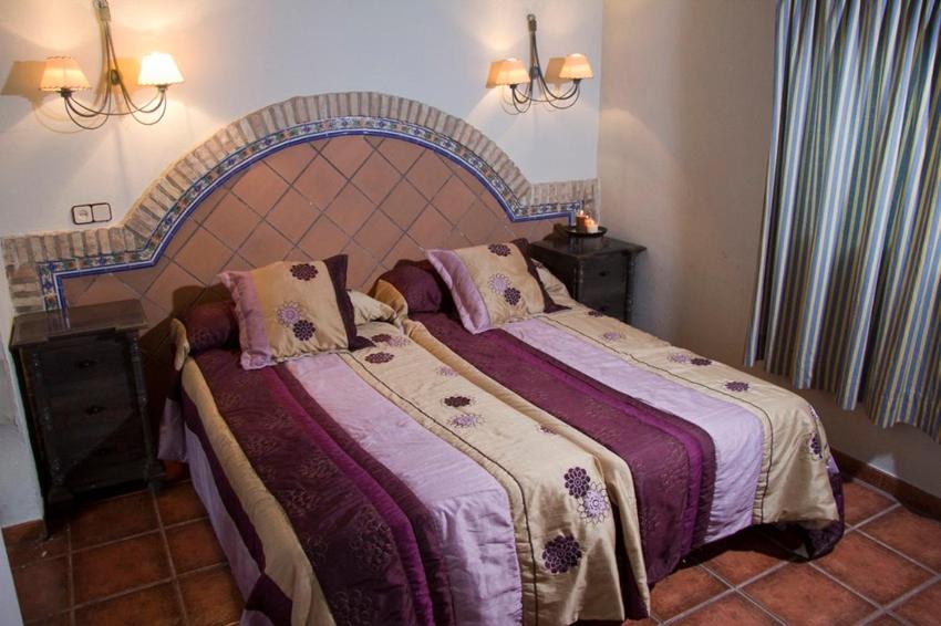 sypialnia z dużym łóżkiem z fioletową pościelą w obiekcie DEHESA LAS BRIDAS, SL w mieście Morón de la Frontera