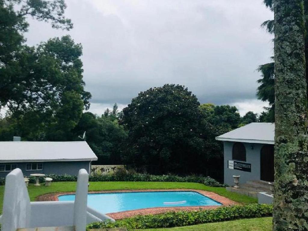 una piscina en un patio con una casa en The Midlands Hotel, en Pietermaritzburg