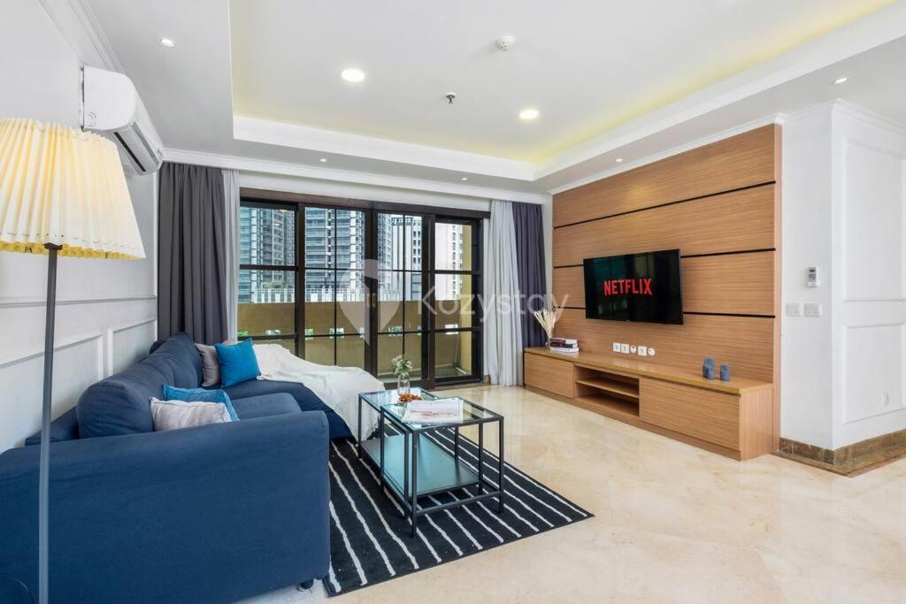 a living room with a blue couch and a tv at VEGA by Kozystay 3BR SCBD in Jakarta