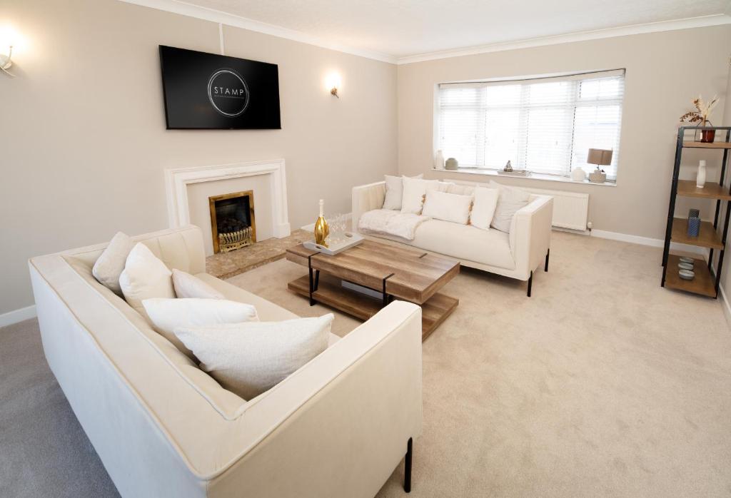 uma sala de estar com dois sofás brancos e uma lareira em The Masters by STAMP SA em Lytham St Annes