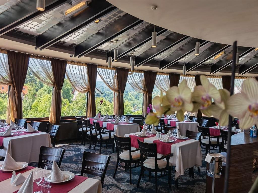 a dining room with tables and chairs and windows at Hotel Belvedere in Braşov