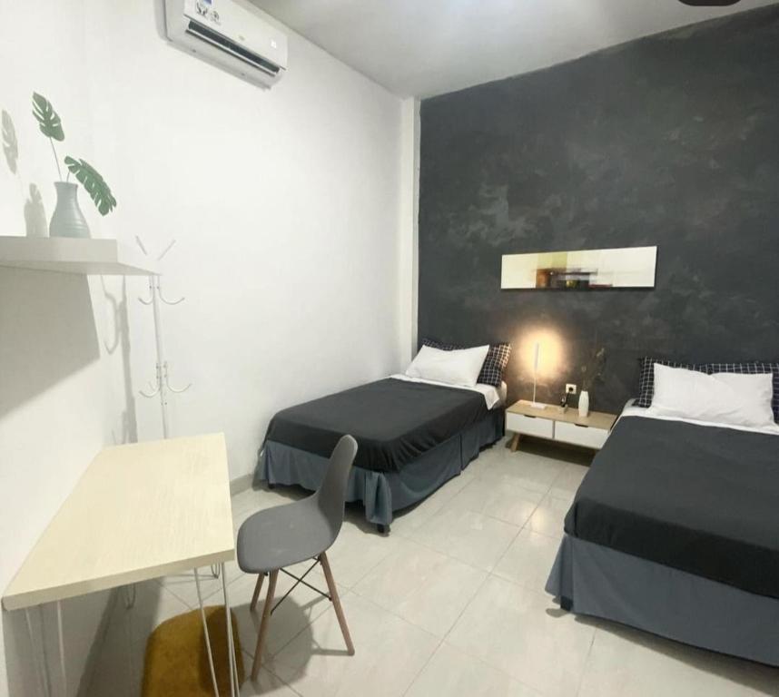 a bedroom with two beds and a table and a chair at Choko Guest House in Solo