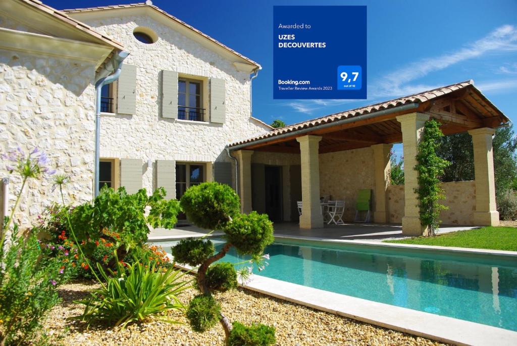 a villa with a swimming pool in front of a house at UZES DECOUVERTES in Uzès