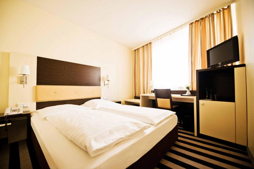 a hotel room with a large bed and a desk at Tante ALMA Bristol Hotel in Frankfurt
