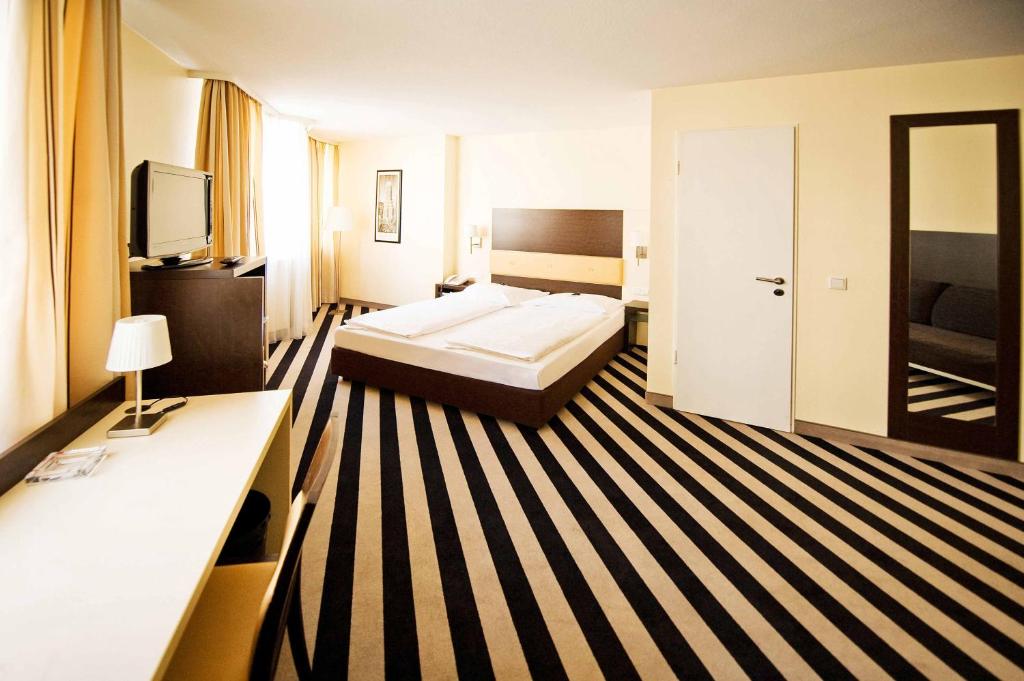 a hotel room with a bed and a television at Bristol Hotel - Frankfurt City in Frankfurt/Main