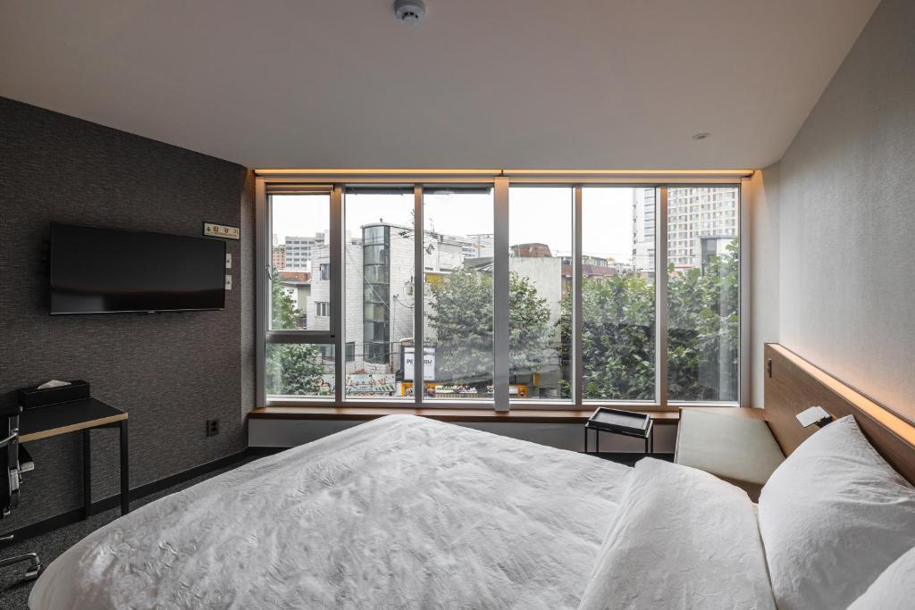 a bedroom with a large bed and a large window at Pillowsopher Hongdae in Seoul