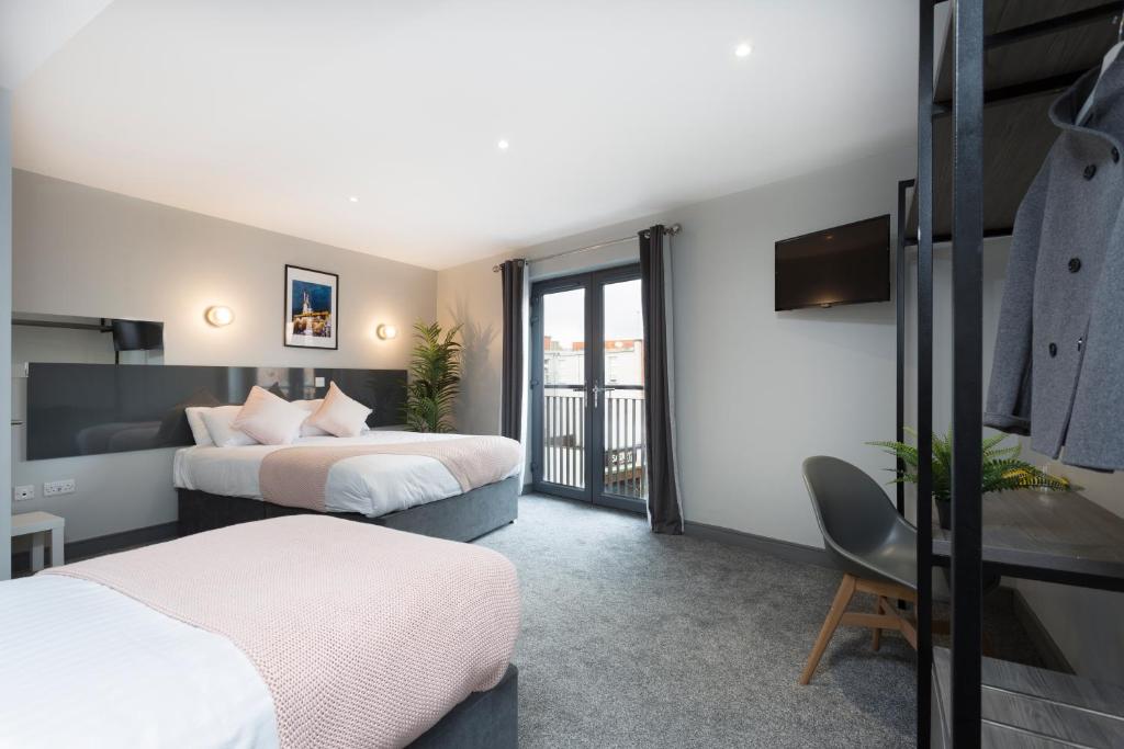 a hotel room with two beds and a balcony at Bank Square Town House in Belfast