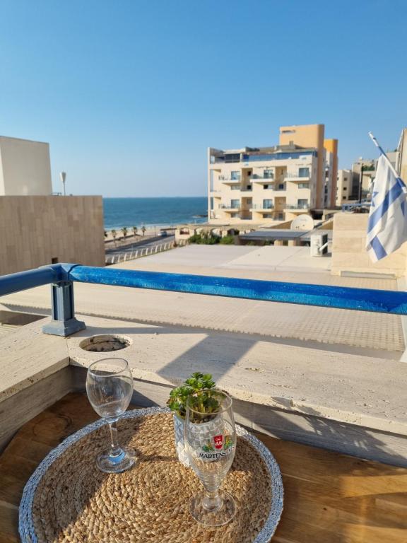 a table with two wine glasses on a balcony at Pearl island suite in Ashkelon