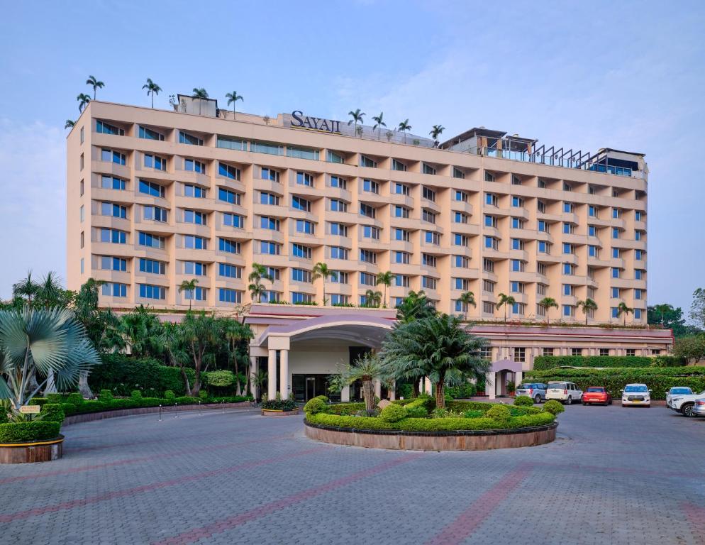 a large hotel with a parking lot in front of it at Sayaji Indore in Indore
