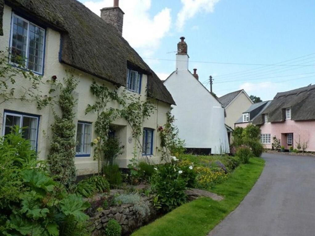 a cottage with a thatched roof and a street at The Pack Horse Exmoor National Park Allerford Riverside Cottage & Apartments in Minehead
